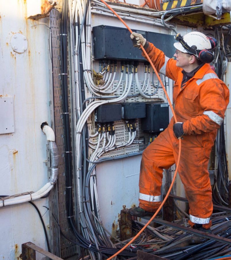 man working with cables on an oil rig